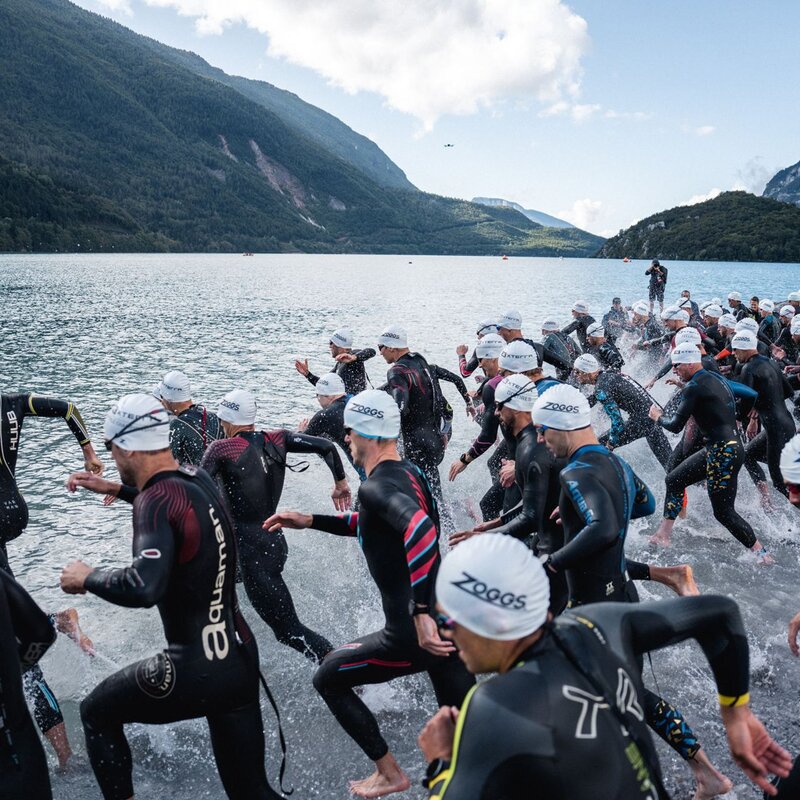 A group of X-Terra participants wearing wetsuits and swimming caps dive into Lake Molveno  | © Alice Russolo, 2023
