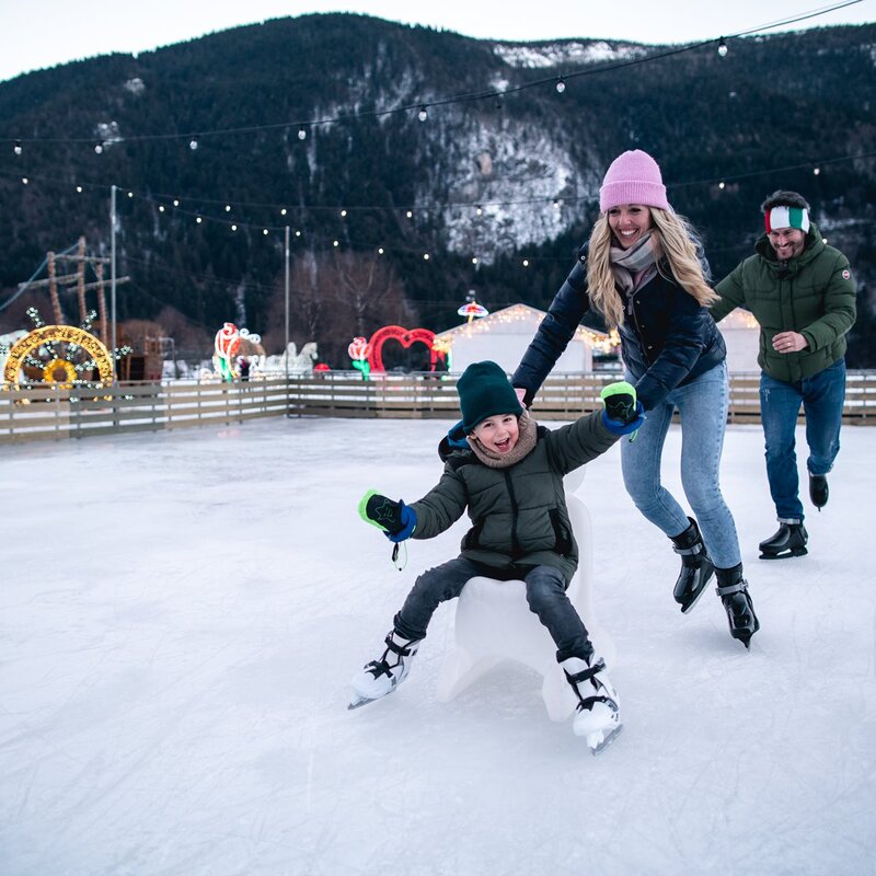 Ein Kind läuft mit seinen Eltern am Ufer des Molveno-Sees Schlittschuh. | © Alice Russolo, 2022