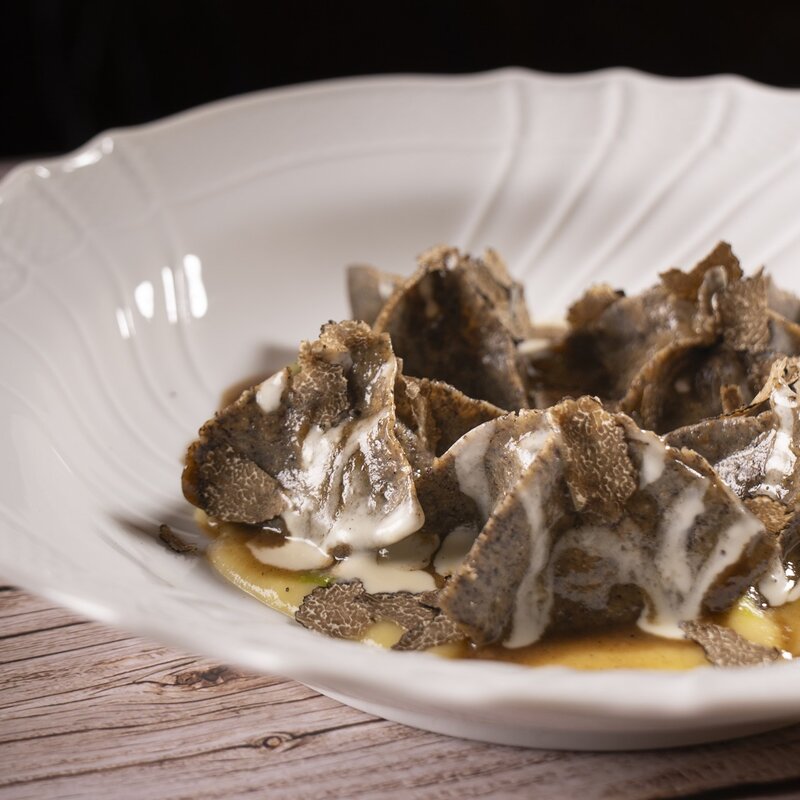 Tortelli di grano saraceno a forma piramidale farciti con coniglio, porri e conditi con burro fuso, crema e abbondanti scaglie di tartufo nero. | © Stefano Caffarri, 2025