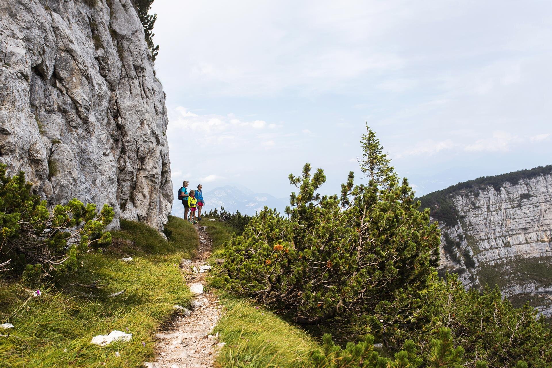 Due bambine con una donna percorrono il sentiero delle aquile sulla Cima Paganella, tra mughi e pareti verticali | © Filippo Frizzera, 2019
