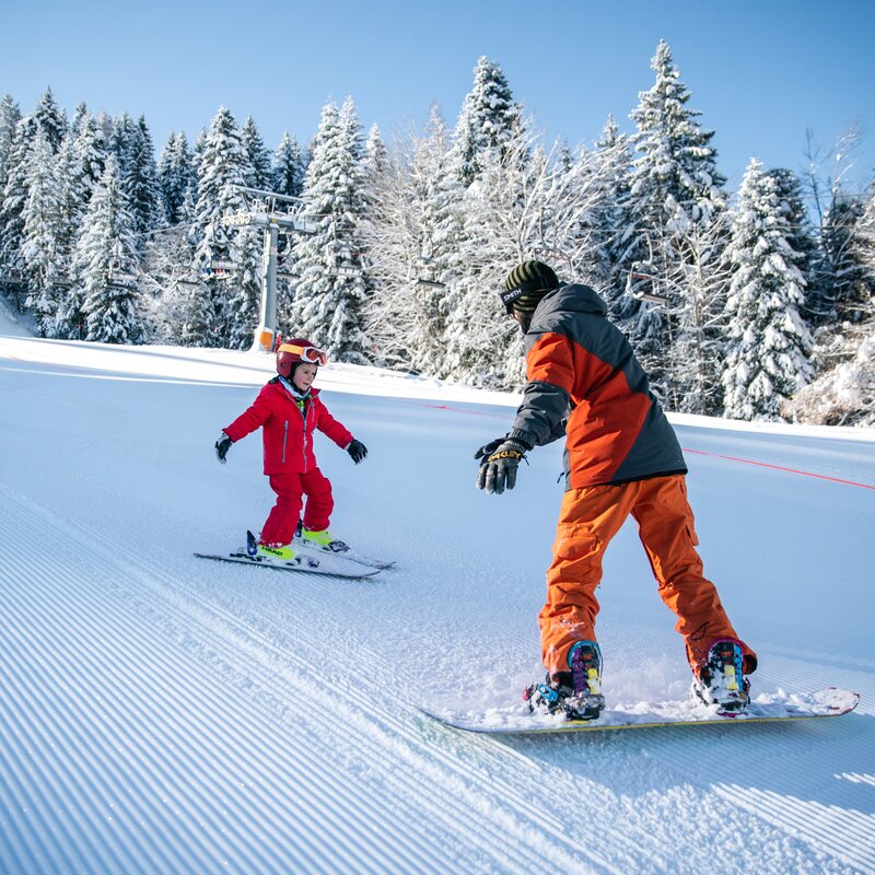 Dad on snowboard and son on skis ski down Paganella ski slopes | © Oliver Astrologo, 2020