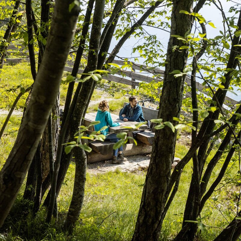Ein Paar macht eine entspannende Pause auf den Picknicktischen im Respiro-Park in Fai della Paganella. | © Massimo Giovannini, 2022