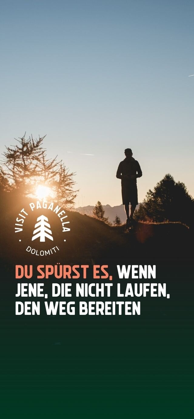 Vertikale Werbegrafik mit der Silhouette eines Mannes im Gegenlicht der Abendsonne in den Bergen. Enthalten sind das "Visit Paganella Dolomiti"-Logo und der Spruch: "DU SPÜRST ES, WENN JENE, DIE NICHT LAUFEN, DEN WEG BEREITEN". | © Filippo Frizzera, 2025