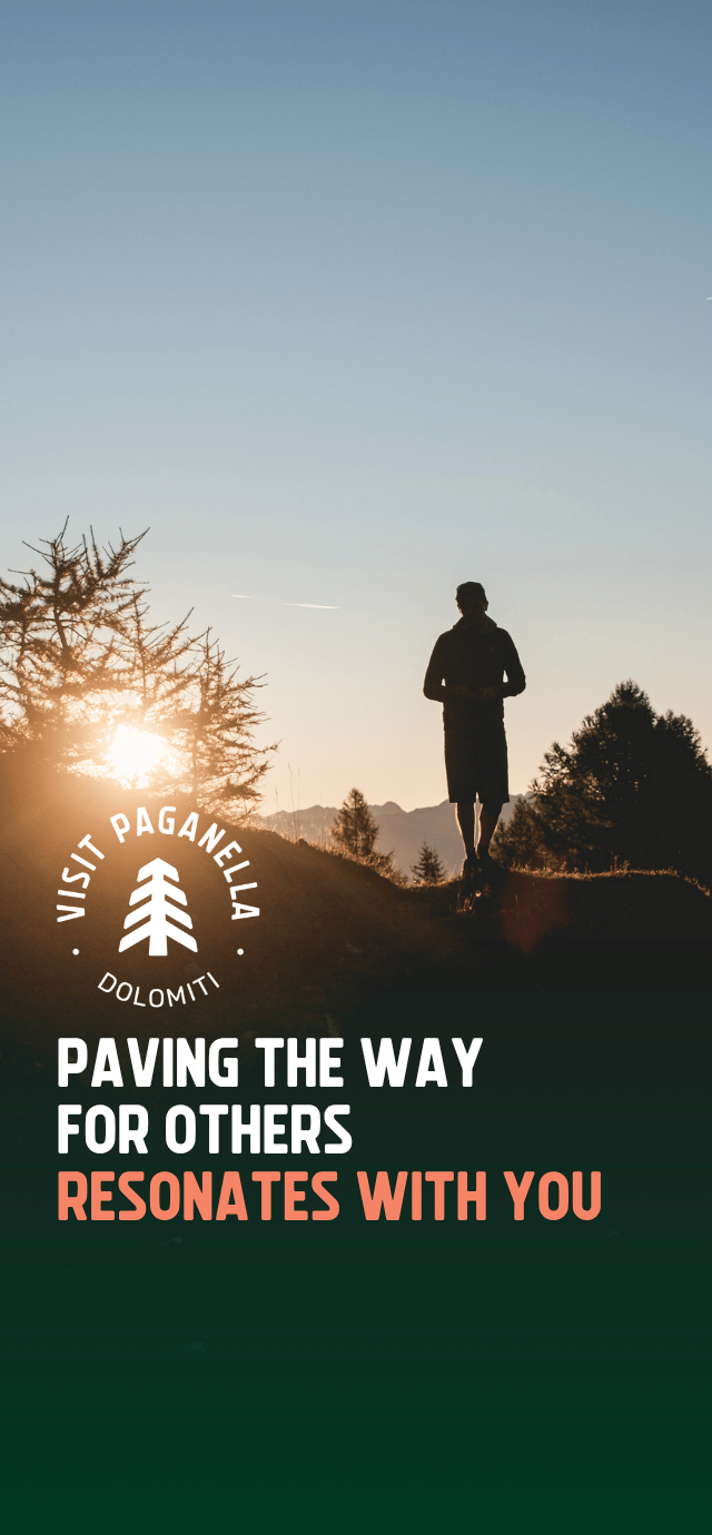 Silhouette of a person standing on a mountain ridge at sunrise, with the sun glowing behind a larch tree. The "Visit Paganella Dolomiti" logo is positioned in the center. Below the logo, the text reads: "PAVING THE WAY FOR OTHERS RESONATES WITH YOU." | © Filippo Frizzera, 2025