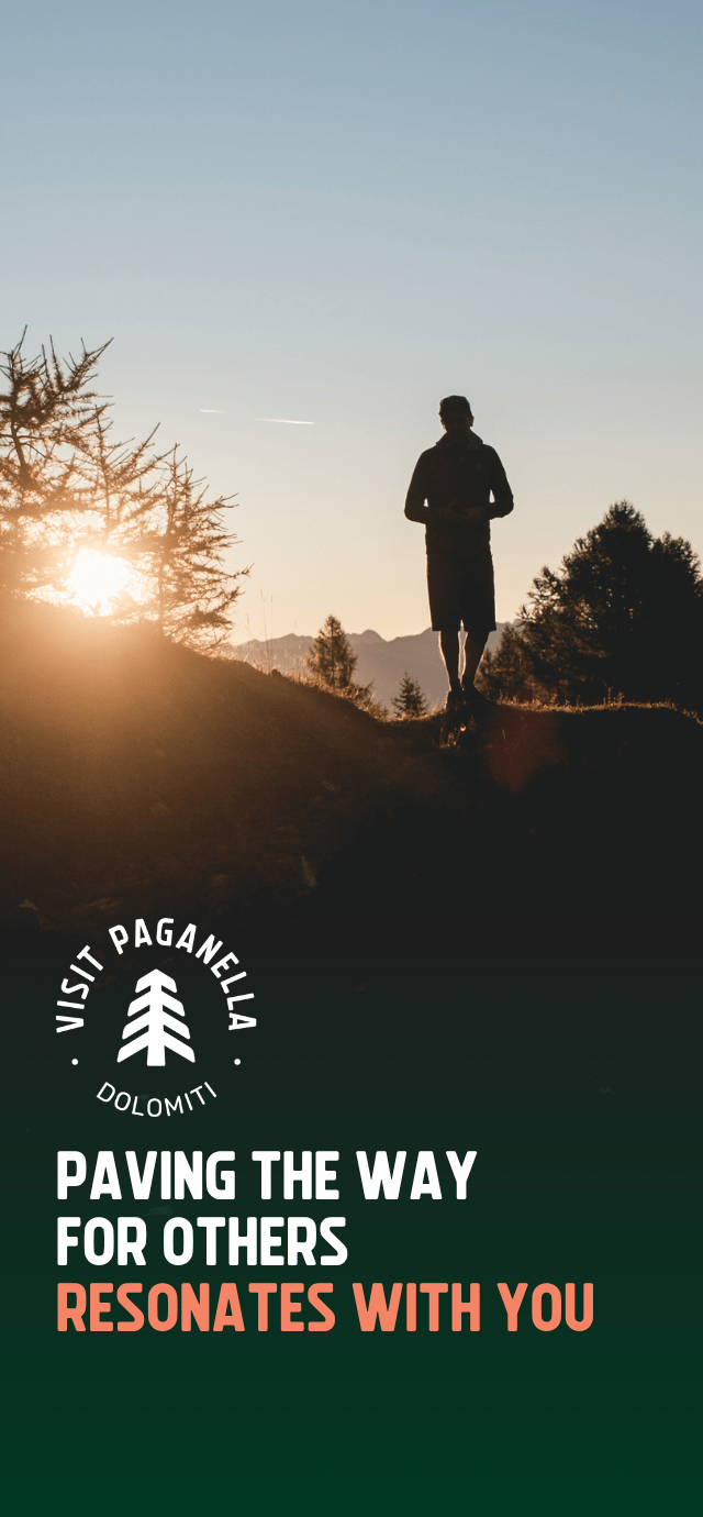 Silhouette of a person standing on a mountain ridge at sunrise, with the sun glowing behind a larch tree. The "Visit Paganella Dolomiti" logo is positioned in the center. Below the logo, the text reads: "PAVING THE WAY FOR OTHERS RESONATES WITH YOU." | © Filippo Frizzera, 2025