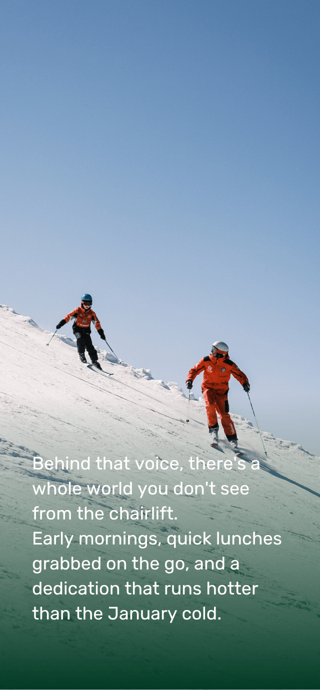 A ski instructor in a red uniform and a child in similar attire descend a steep snow-covered slope, leaving tracks in the fresh snow under a clear blue sky.  Overlay text: Behind that voice, there's a whole world you don't see from the chairlift. Early mornings, quick lunches grabbed on the go, and a dedication that runs hotter than the January cold. | © Filippo Frizzera, 2025