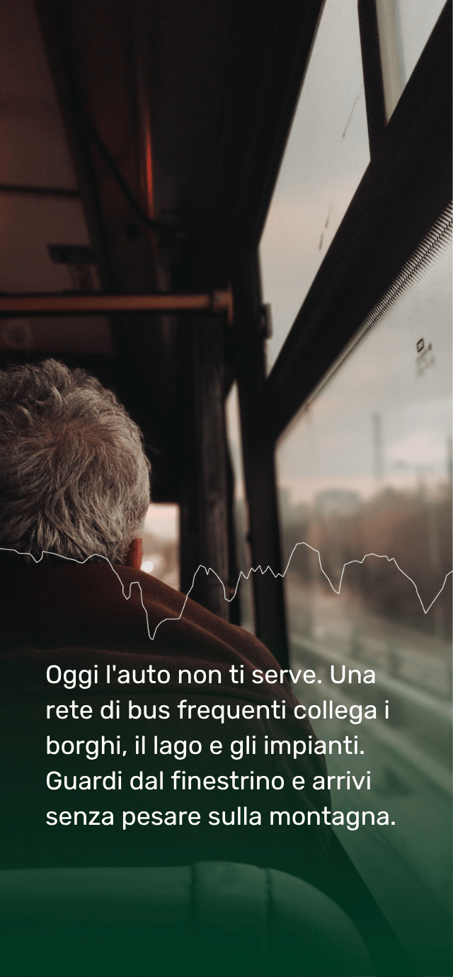 La visuale dall'interno di un autobus, che inquadra di spalle un passeggero con i capelli grigi seduto a guardare il panorama fuori dal finestrino. L'atmosfera è caratterizzata da luci calde e ombre. Nella parte inferiore, su uno sfondo sfumato verde scuro, è presente il seguente testo in bianco: "Oggi l'auto non ti serve. Una rete di bus frequenti collega i borghi, il lago e gli impianti. Guardi dal finestrino e arrivi senza pesare sulla montagna." | © Tuğba Özsoy
