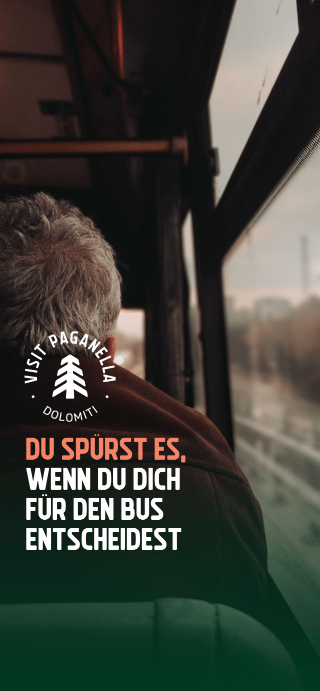Die Ansicht aus dem Inneren eines Busses, die über die Schulter eines Fahrgastes mit grauem Haar blickt, der aus dem Fenster schaut. Die Atmosphäre ist von warmem Licht und Schatten geprägt. Unten links befindet sich auf einem dunkelgrünen Farbverlauf ein kreisförmiges weißes Logo mit einer stilisierten Tanne in der Mitte und den Wörtern "VISIT PAGANELLA" und "DOLOMITI". Unter dem Logo steht in Großbuchstaben der folgende Text: "DU SPÜRST ES," (in Pfirsichfarbe) "WENN DU DICH FÜR DEN BUS ENTSCHEIDEST" (in Weiß) | © Tuğba Özsoy